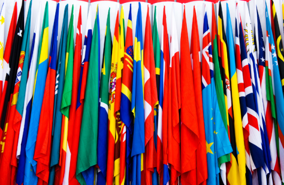 A bunch of flags grouped thickly together against a wall. 